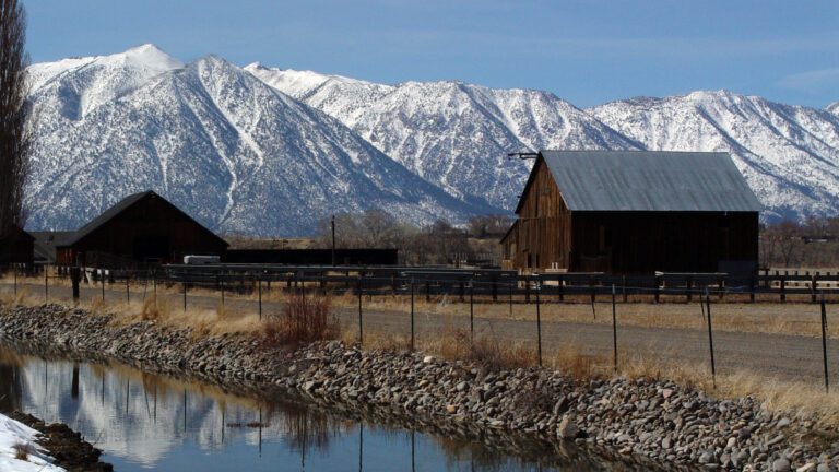 Rustic Barn with Snowy Mountains and Reflection 4K Wallpaper