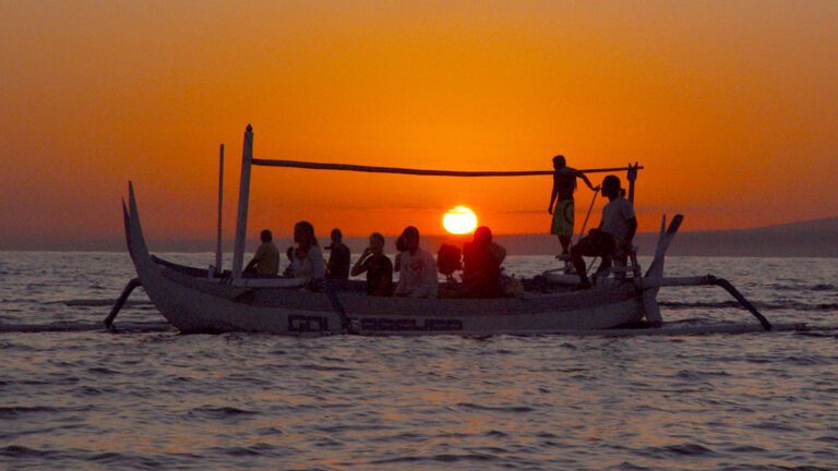 Silhouette of people on a boat at sunrise in Bali during dolphin watching
