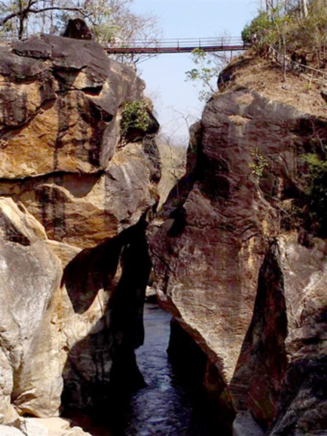 Narrow rock canyon with a suspension bridge crossing above a river in Thailand