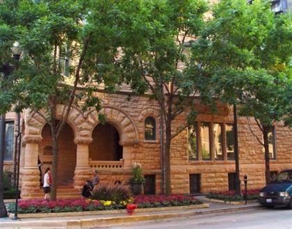 Historic stone building along a tree-lined street in downtown Chicago.