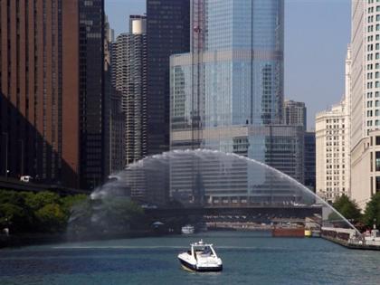 Sightseeing boat traveling along the Chicago River surrounded by skyscrapers.