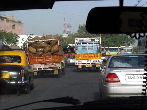 Busy traffic in New Delhi featuring cars, trucks, and taxis.