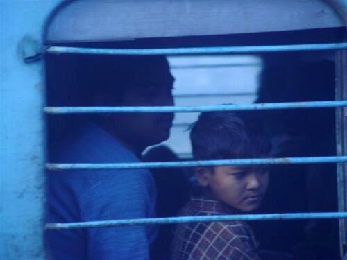Young passenger looking through the barred window of a train in India.