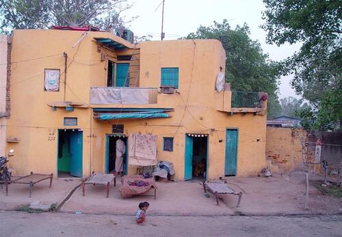 Traditional yellow home in a village along a railway route in northern India.
